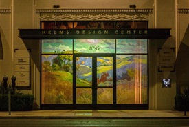 Photograph of Helms Design Center windows showing exhibition Projecting Possibilities and featuring artist Alexey Steele including landscape artwork