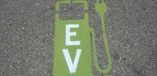 Photograph of pavement with image of electric vehicle charging station painted in green with white EV lettering