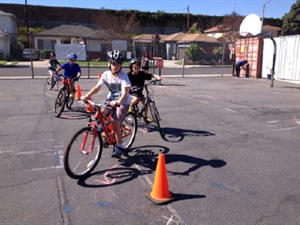 Photograph of children on bikes in a training exercise riding around traffic cones