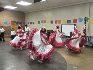 Young folkorico dancers in white, pink, and red dresses dancing