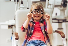 Little child in the optometrist chair behind a Phoropter